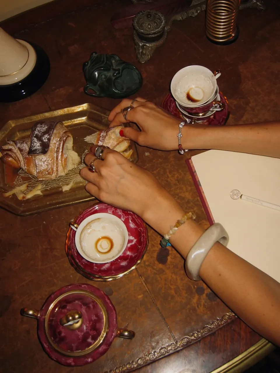 Coffee, pastries and hands at an antique desk in Giordano Segreto